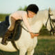 A small child on a grey pony, hugging her beloved pony club mount that is fed a balanced diet